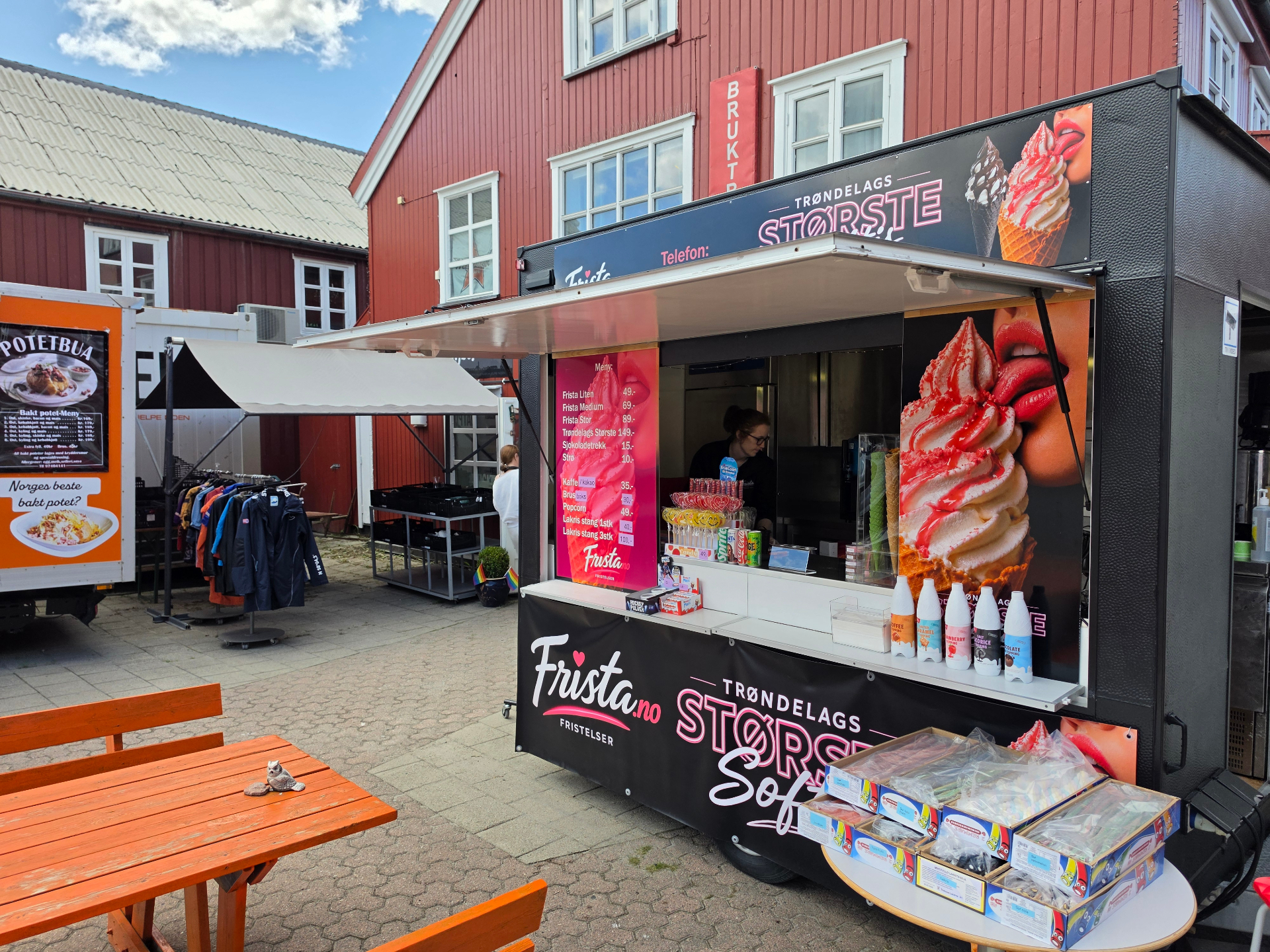 Fristas stand sett fra siden med bord foran og produkter på disken